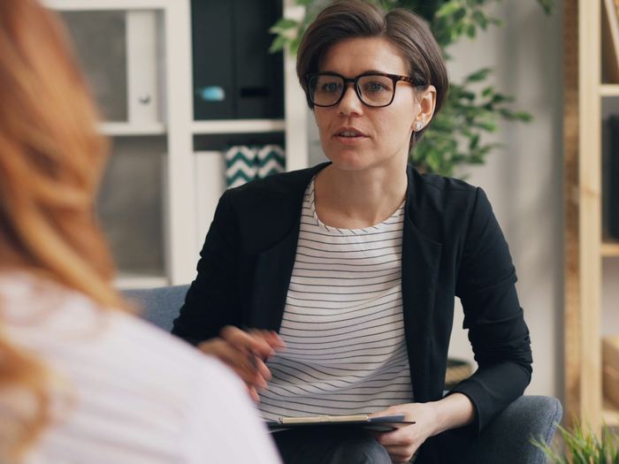 A counselor speaks gently with a client during a calm, private conversation